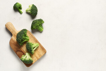 Wooden board with fresh broccoli cabbages on white background