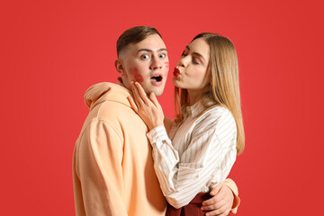 Shocked young couple on red background. Valentine's Day celebration