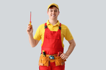 Male electrician with screwdriver on light background