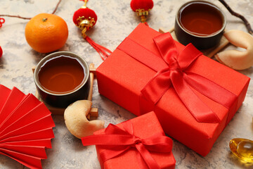 Gift boxes with cups of tea, fortune cookies and Chinese symbols on grunge background. New Year celebration