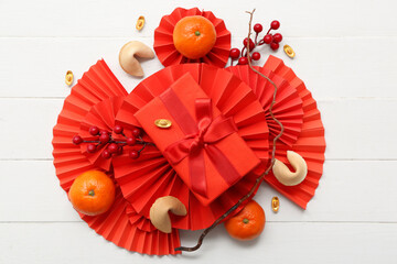 Gift box with fortune cookies, mandarins and Chinese symbols on white wooden background. New Year...