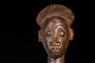 Fototapeta na wymiar Close-up of an African female figure carved in wood isolated on black. Traditional African art with balanced shapes and volumes and a beautiful dark brown patina.