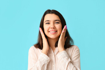 Young happy smiling woman with hands near face on blue background