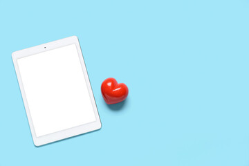 Tablet computer with red heart on blue background. Concept of online dating