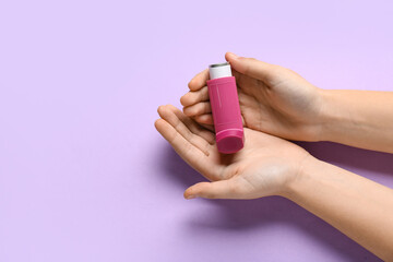 Child's hands with asthma inhaler on lilac background - obrazy, fototapety, plakaty