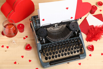 Beautiful composition with vintage typewriter, glass of wine and decor for Valentine's day on wooden background