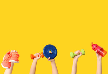 Female hands with sports equipment and shoes on yellow background