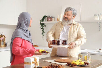 Mature Muslim couple with tea celebrating Ramadan at table in kitchen