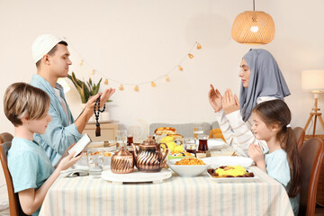 Muslim family praying before dinner at home. Ramadan celebration