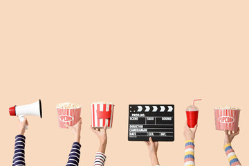 Many hands with movie clapper, buckets of popcorn and megaphone on beige background