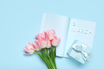 Text 8 MARCH with gift box, notebook and beautiful pink tulips on blue background. International Women's Day