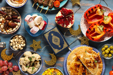 Traditional Eastern dishes and Koran on blue wooden table. Ramadan celebration