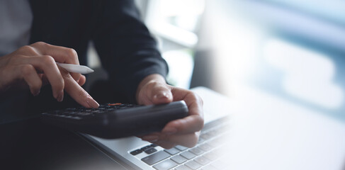 closeup of business woman, accountant working at office, using calculator to calculate home...