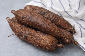 Fresh whole cassava roots on grey table, closeup