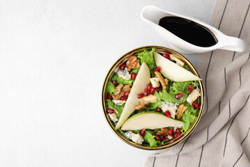 Delicious pear salad in bowl and sauce on light table, top view. Space for text