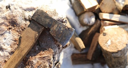 Metal axe on wooden log and pile of wood outdoors on sunny winter day, top view. Space for text