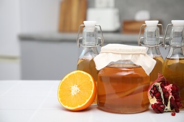Homemade fermented kombucha and fresh fruits on white table in kitchen. Space for text