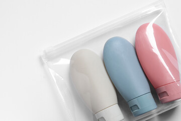 Obraz premium Cosmetic travel kit in plastic bag on white background, top view. Space for text