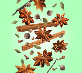 Fototapeta na wymiar Different aromatic spices falling on green background