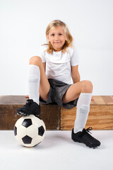 Young male child with long blond hair playing with his soccer ball