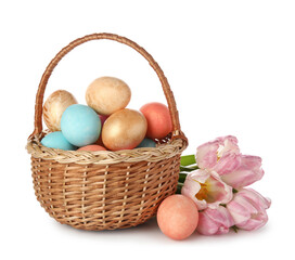 Basket with painted Easter eggs and pink tulips on white background