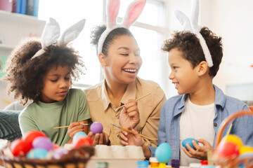 Happy mother with cute kids wearing bunny ears painting and decoration easter eggs celebration Easter at home