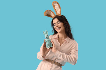 Beautiful woman in bunny ears with Easter rabbit on blue background