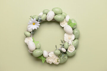 Easter wreath with white flowers, eggs and butterflies on light green background