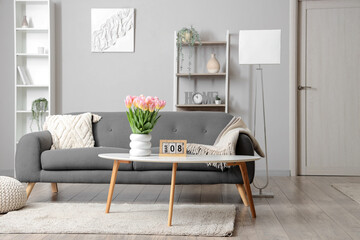 Interior of living room with sofa and tulips in vase for International Women's Day