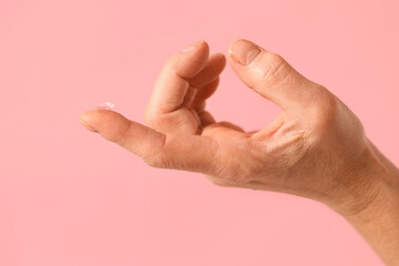 Female hand with contact lens on pink background