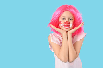 Funny girl in clown costume on blue background. April Fool's Day celebration