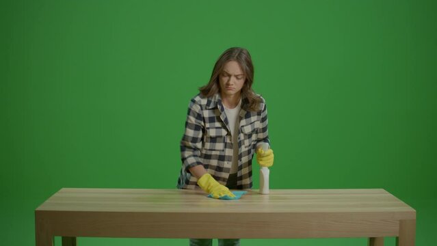 Green Screen.An Angry and Tired Young Woman Wear Yellow Protective Rubber Gloves ,Holding a Spray Bottle and Cleaning a Table. Multi-functional Cleaning Tools.