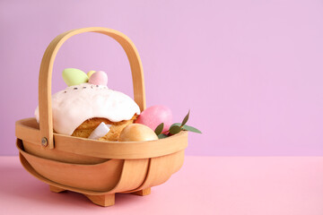 Composition with delicious Easter cake and painted eggs in wooden basket on color background