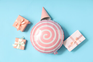 Balloon with gift boxes and party hat on blue background