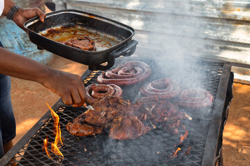 african american man by the barbeque , braai, cooking beef brisket and sausage