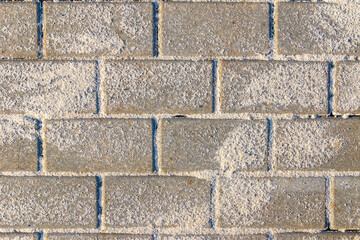 Obraz premium Horizontal texture of paving slabs made of artificial stone or concrete is laid and seams are covered with sand, the remains of which are on the surface, selective focus