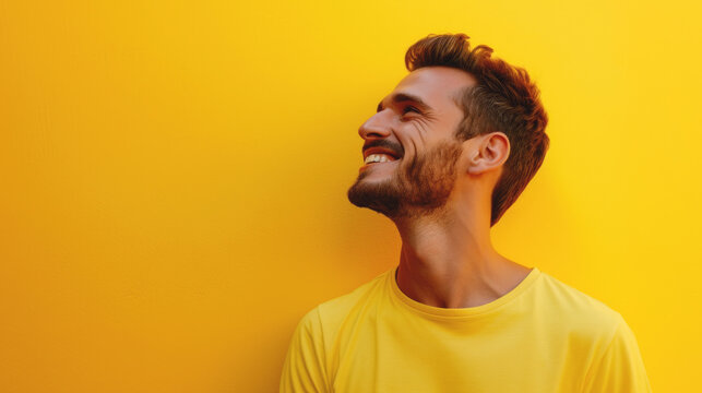 Handsome guy with trendy haircut and well-groomed beard in stylish yellow shirt standing against plain yellow background with toothy smile
