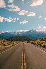 Vertical shot of a road with the magnificent mountains under the blue sky captured in California