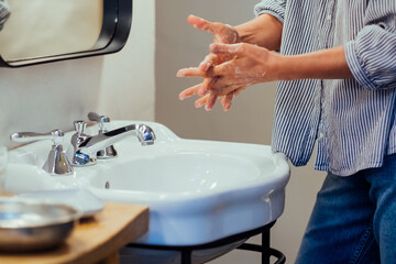 Close-up of a person's hands being washed with soap and water at a sink. Personal hygiene. 