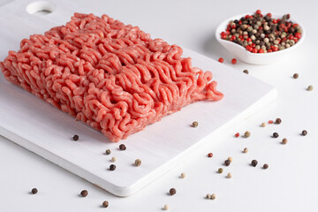 Fresh raw minced meat and peppers on a white table, close-up