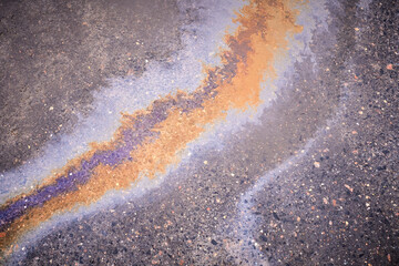 Fototapeta na wymiar Textured stain of fuel or oil on wet asphalt on a rainy day. The concept of environmental pollution