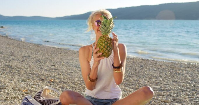 Women, friends and beach or pictures with cellphone for social media post, pineapple or summer. Female people, funny and paradise holiday or tropical for Bali adventure or ocean, snack or internet