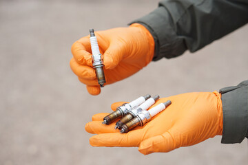 Close up mechanic hands hold old spark plug, spare part of car engine. Concept, machine...