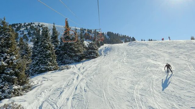 Chair-lift at ski resort against snowcapped forest tree and mountain peaks covered in snow landscape in luxury winter alpine resort. Winter leisure sports, recreation and travel.