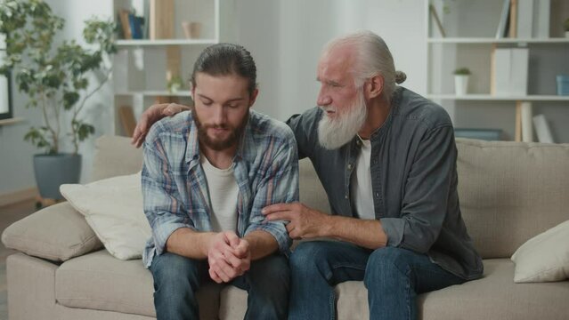 Deep conversation between generations young man and elder on the couch discuss life, experience exchange, heartfelt communication, emotional support, understanding differences mentoring, family values
