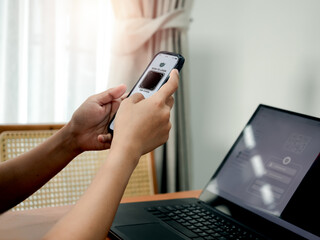 QR Code, multi factor authentication security concept. Digital scanner, graphic symbol on smartphone camera display holding by businessman hand, scanning for login on laptop computer screen.
