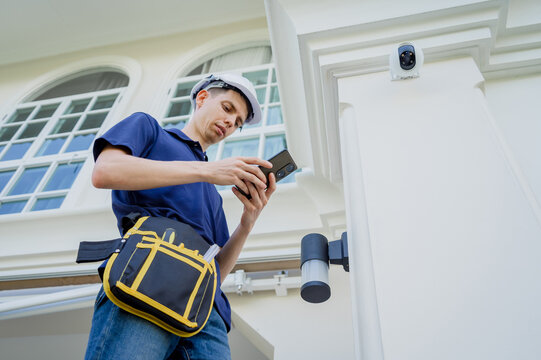 A technician sets up a CCTV camera on the facade of a residential building.