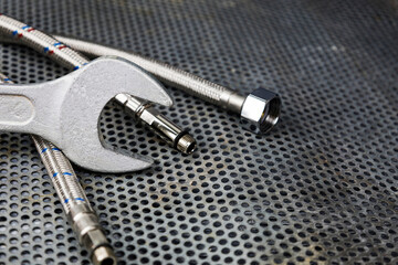 Plumbing parts, accessories and tools on a gray metal background with a dedicated copy space.
