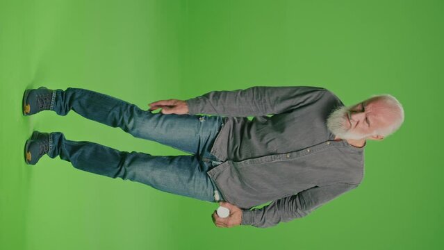 Vertical View.Green Screen. An Old Man Who Has Pain in His Leg.An Elderly Man Feeling Sick, Having Painful Leg Feelings and He Chooses Pills. Health in Adulthood.