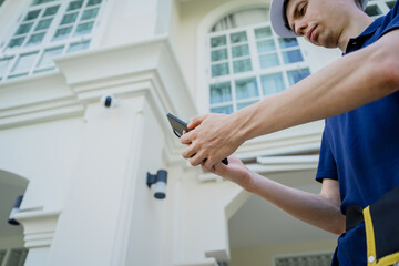 Obraz premium A technician sets up a CCTV camera on the facade of a residential building.